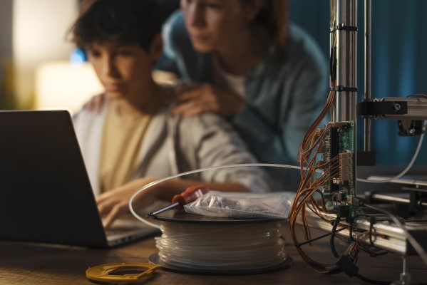 Desenfoque de un adolescente junto a su madre que aprenden a modelar e imprimir en 3D, para futuros proyectos escolares.